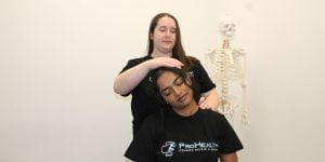 Dr. Natalie, chiropractor, providing neck pain treatment to a female patient at ProHealth Physiotherapy Oshawa. Dr. Natalie is standing beside the treatment table, and the patient is seated comfortably. Dr. Natalie's hands are gently manipulating the patient's neck, providing chiropractic adjustments to alleviate neck pain and improve spinal alignment. The patient is receiving personalized and attentive care to address their specific needs. With Dr. Natalie's expertise, the patient can experience relief from their neck pain and improve their overall well-being.